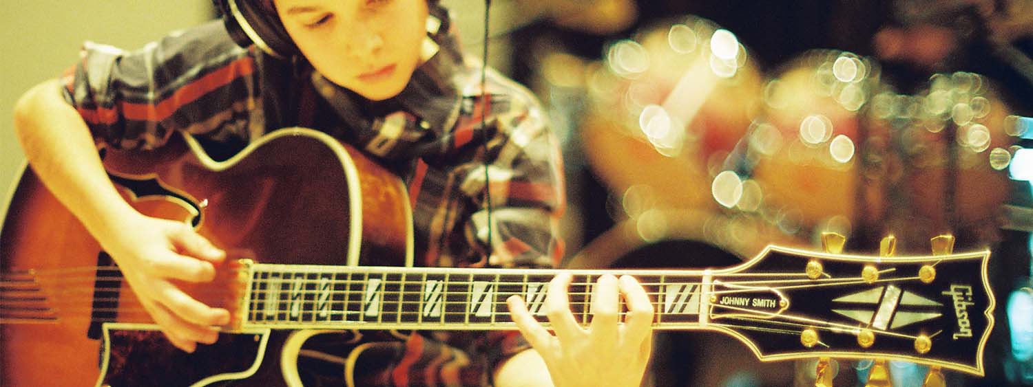 A young musician playing guitar in a recording studio